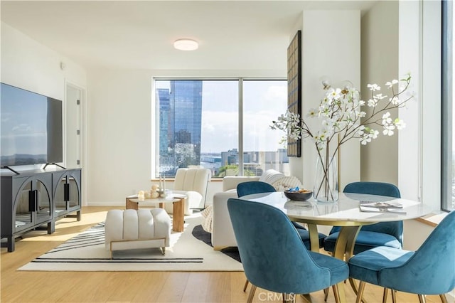 dining space with baseboards, wood finished floors, and plenty of natural light