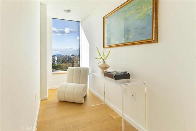 sitting room featuring visible vents, light wood-style flooring, and baseboards