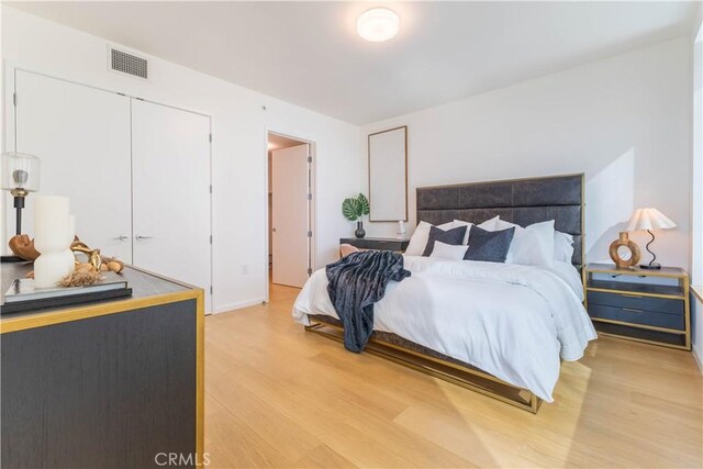 bedroom featuring light wood finished floors, a closet, and visible vents