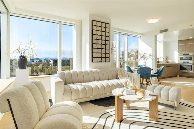 living room with visible vents, light wood-type flooring, and a city view