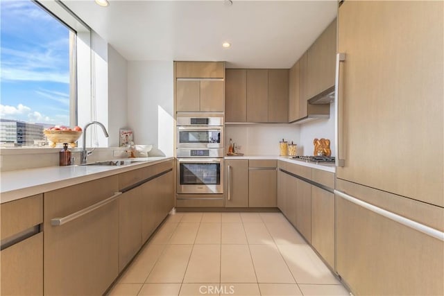 kitchen featuring light tile patterned floors, a sink, stainless steel appliances, and light countertops