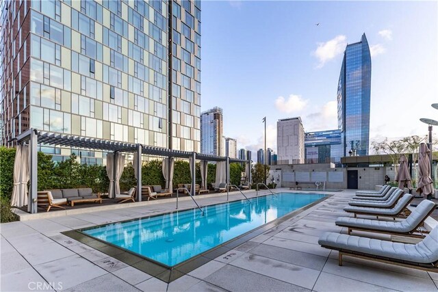 pool with an outdoor living space, a view of city, a patio area, and a pergola