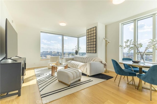 living room featuring light wood-style flooring, a wealth of natural light, and baseboards