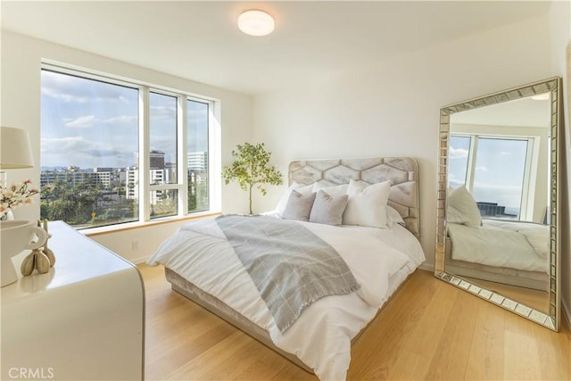 bedroom featuring a view of city and light wood finished floors