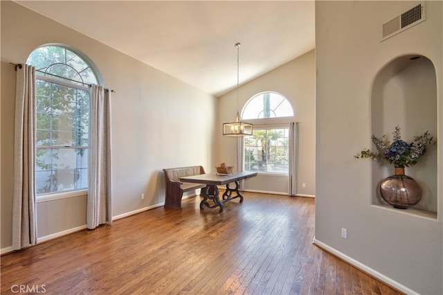 dining space featuring wood-type flooring, vaulted ceiling, and baseboards