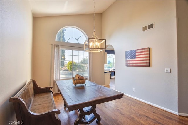 dining room with wood finished floors, healthy amount of natural light, high vaulted ceiling, and baseboards