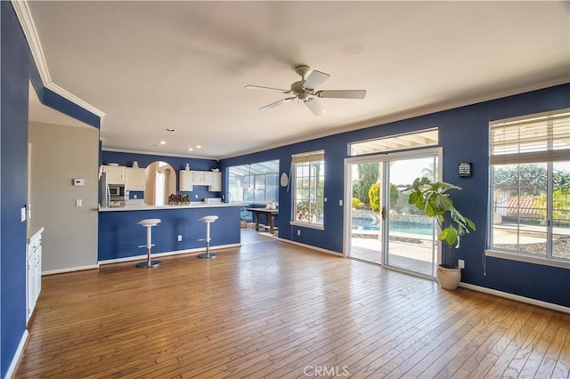 unfurnished living room featuring crown molding, healthy amount of natural light, baseboards, and ceiling fan