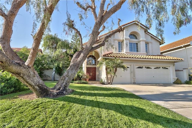 mediterranean / spanish house with a garage, a tile roof, concrete driveway, stucco siding, and a front yard