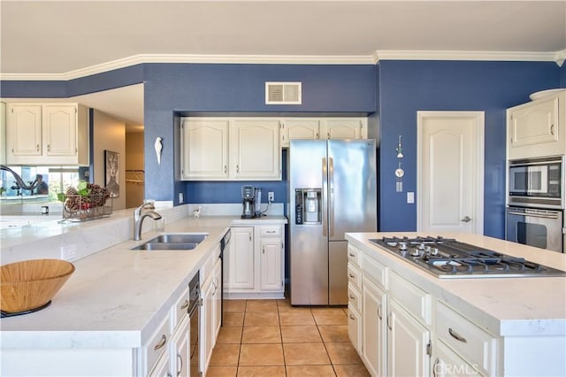 kitchen featuring appliances with stainless steel finishes, a sink, crown molding, white cabinetry, and light stone counters