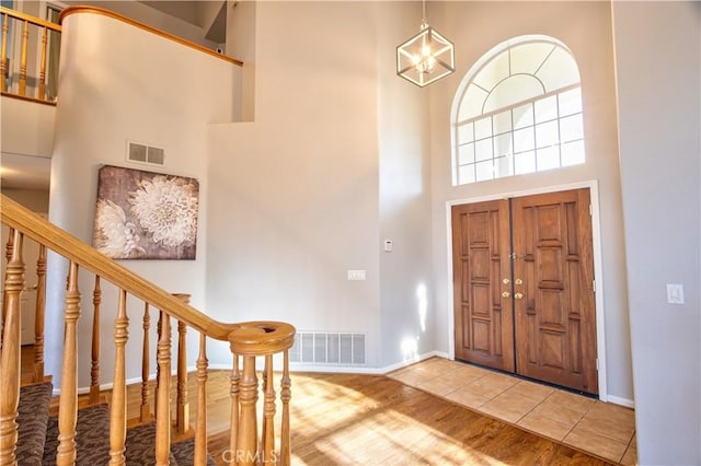entryway with a high ceiling, stairway, baseboards, and a chandelier