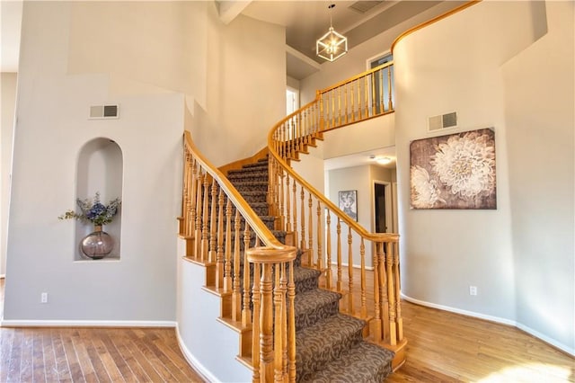 stairs with a towering ceiling, wood finished floors, and baseboards
