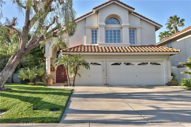 mediterranean / spanish home with a garage, concrete driveway, and a tiled roof