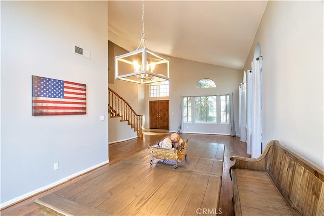 living area featuring a chandelier, high vaulted ceiling, stairway, wood-type flooring, and baseboards