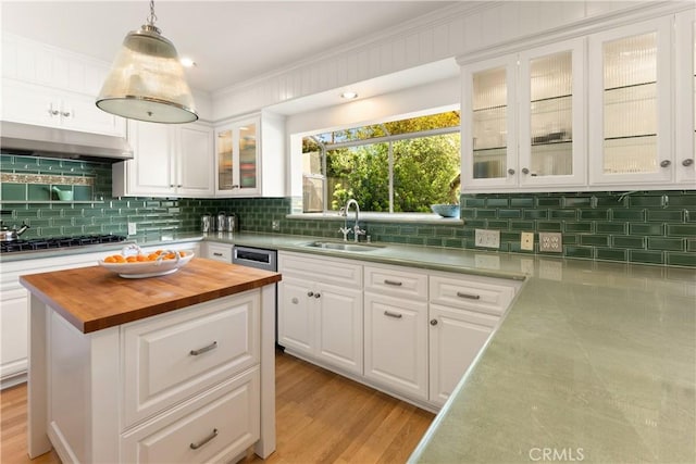 kitchen with white cabinetry, tasteful backsplash, a sink, wooden counters, and under cabinet range hood