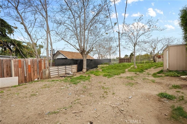 view of yard featuring fence, an outbuilding, and a storage shed