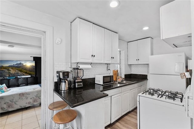 kitchen with recessed lighting, a sink, white appliances, decorative backsplash, and white cabinetry