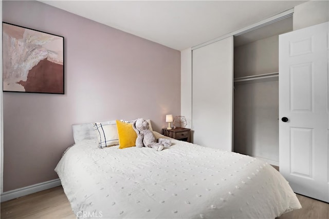 bedroom featuring baseboards, wood finished floors, and a closet