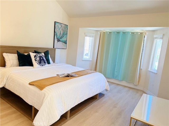 bedroom with light wood-style floors and lofted ceiling