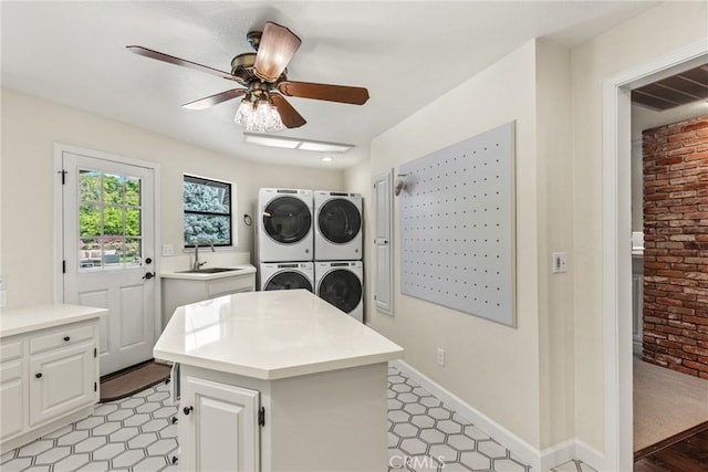 laundry room featuring a ceiling fan, a sink, brick wall, stacked washer and clothes dryer, and independent washer and dryer