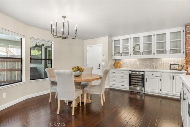 dining room with baseboards, dark wood-style flooring, a chandelier, and wine cooler