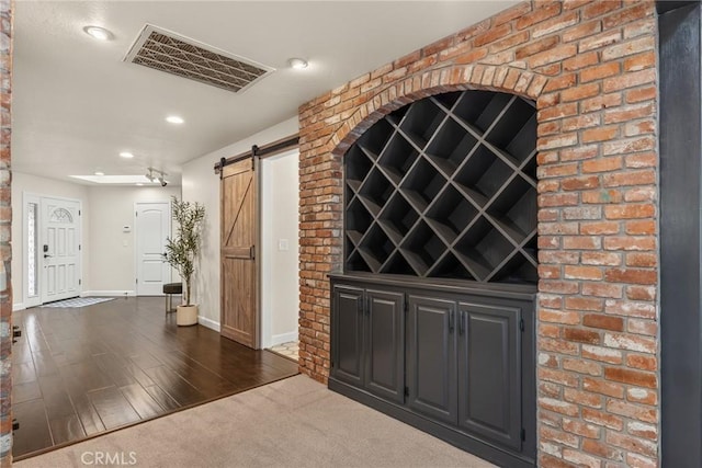 wine cellar featuring a barn door, recessed lighting, visible vents, baseboards, and dark wood-style flooring
