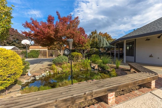 view of yard featuring fence and a garden pond