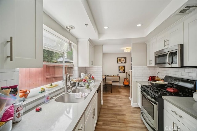 kitchen featuring light wood finished floors, a sink, visible vents, white cabinetry, and appliances with stainless steel finishes