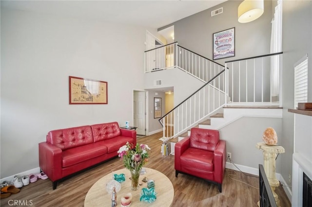 living room with baseboards, wood finished floors, stairs, and visible vents