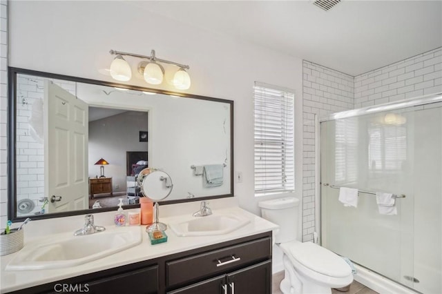 ensuite bathroom featuring double vanity, connected bathroom, a stall shower, and a sink