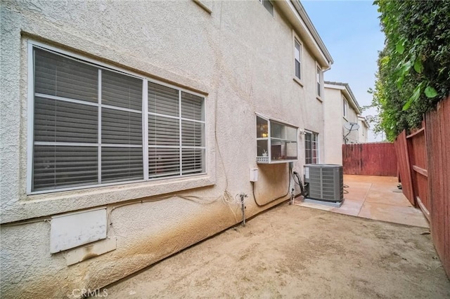 view of side of home with central air condition unit, a fenced backyard, a patio, and stucco siding