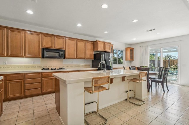 1450 Oakpoint Ave, Chula Vista, CA 91913 - kitchen with black microwave, refrigerator with ice dispenser, brown cabinetry, and recessed lighting