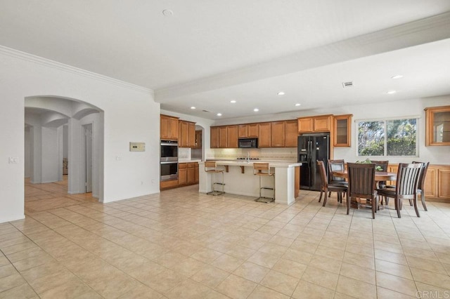 1450 Oakpoint Ave, Chula Vista, CA 91913 - kitchen featuring black appliances, light countertops, a kitchen bar, brown cabinetry, and arched walkways