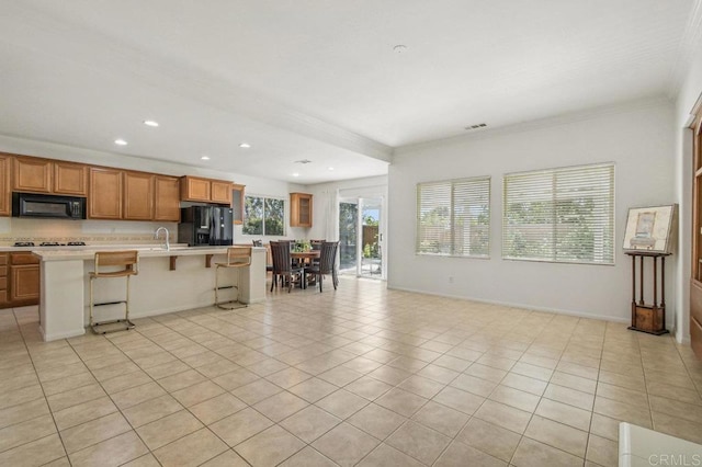 1450 Oakpoint Ave, Chula Vista, CA 91913 - kitchen featuring black appliances, ornamental molding, light countertops, a kitchen bar, and a kitchen island with sink