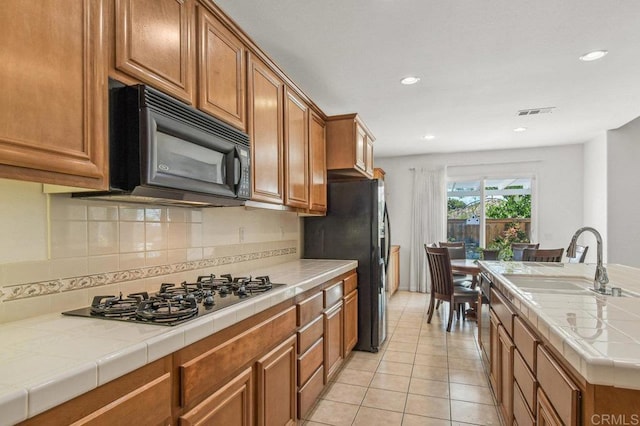 1450 Oakpoint Ave, Chula Vista, CA 91913 - kitchen with black appliances, tile countertops, brown cabinets, tasteful backsplash, and light tile patterned floors