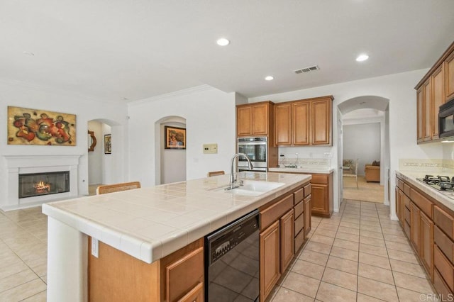 1450 Oakpoint Ave, Chula Vista, CA 91913 - kitchen with black appliances, arched walkways, light tile patterned floors, tile countertops, and a glass covered fireplace