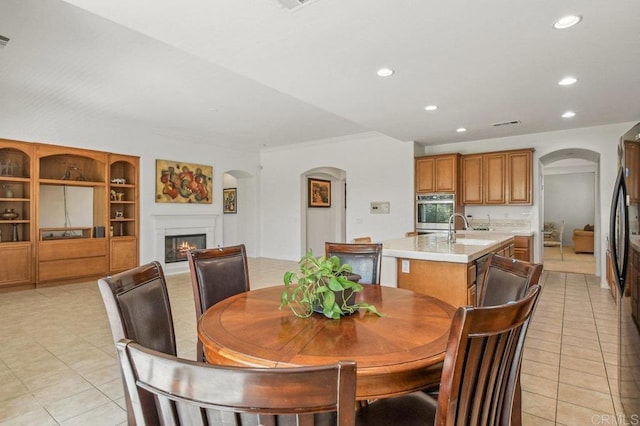 1450 Oakpoint Ave, Chula Vista, CA 91913 - dining room with arched walkways, a warm lit fireplace, recessed lighting, light tile patterned floors, and crown molding