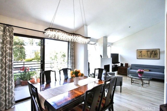 dining room with light wood-style floors, lofted ceiling, and an inviting chandelier