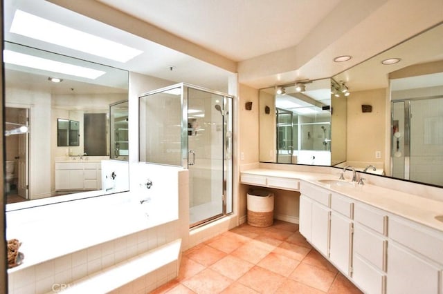 bathroom with a skylight, tile patterned floors, vanity, and a stall shower