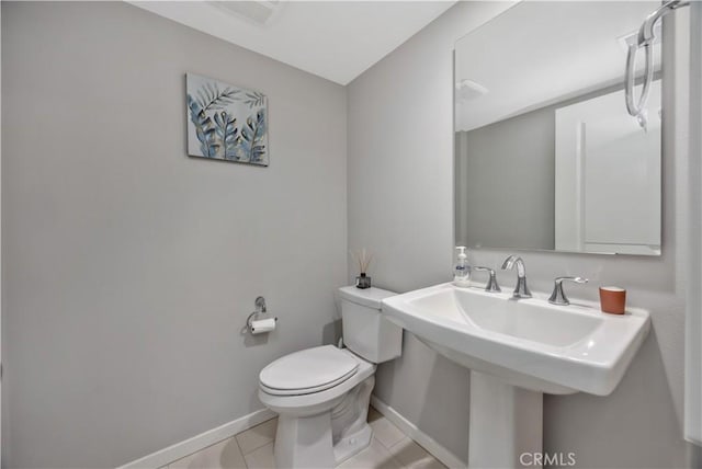 half bathroom featuring tile patterned floors, visible vents, toilet, a sink, and baseboards