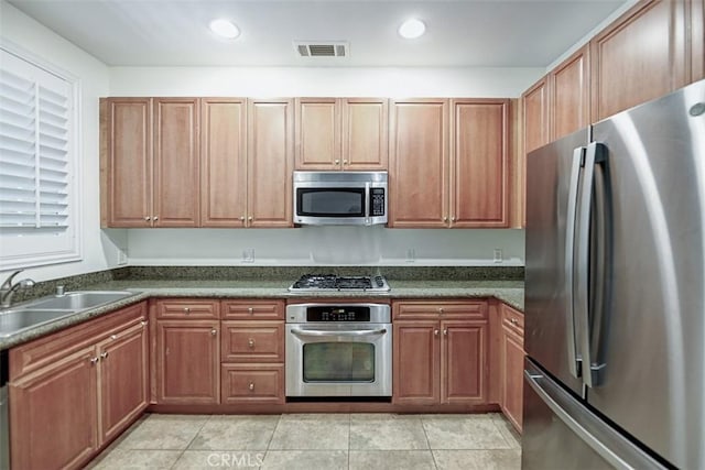 kitchen featuring dark countertops, visible vents, light tile patterned floors, a sink, and appliances with stainless steel finishes