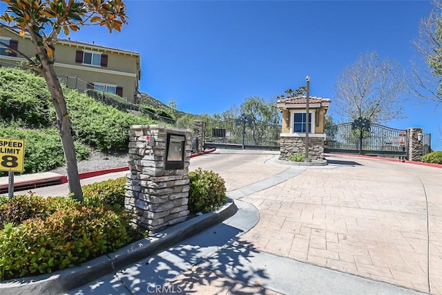view of street featuring a gate, a gated entry, and curbs
