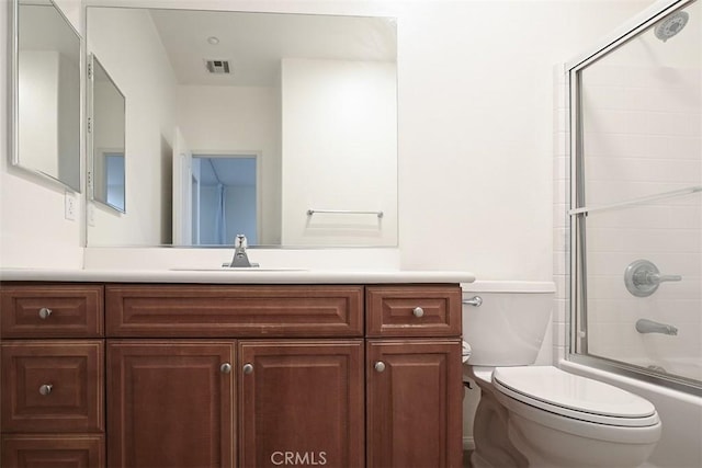 full bathroom featuring combined bath / shower with glass door, visible vents, vanity, and toilet