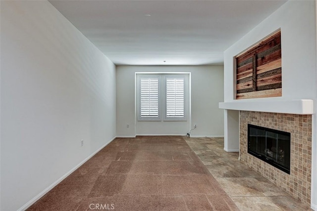 unfurnished living room featuring a tile fireplace and baseboards