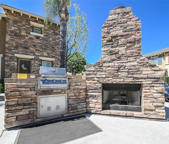 view of patio / terrace with an outdoor stone fireplace, exterior kitchen, and area for grilling