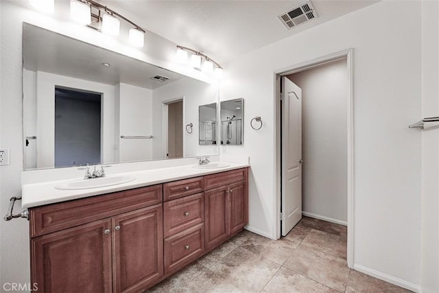 bathroom with double vanity, visible vents, baseboards, and a sink