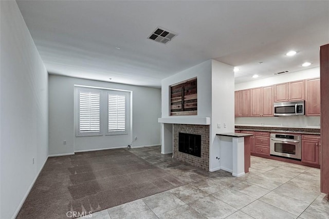 unfurnished living room featuring baseboards, a tile fireplace, visible vents, and recessed lighting