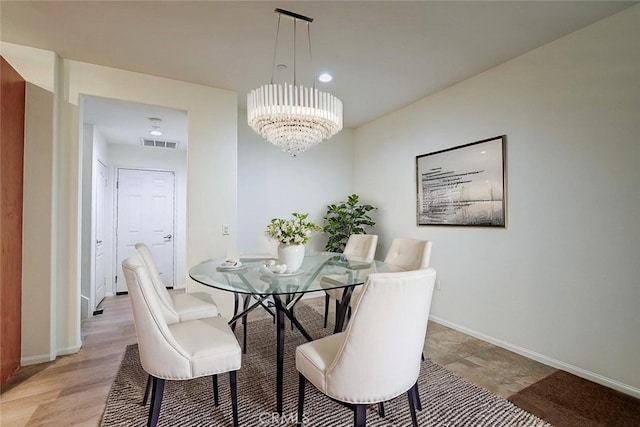 dining area with baseboards, visible vents, and a notable chandelier