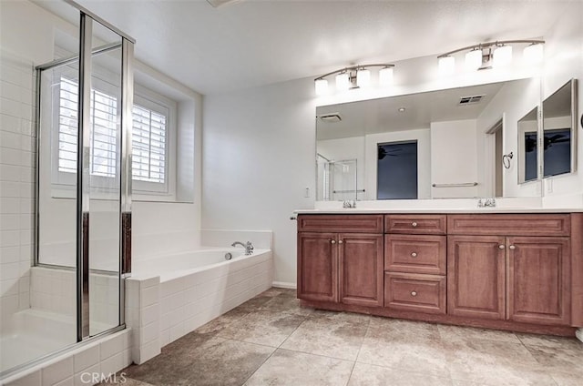 full bath featuring a bath, double vanity, a stall shower, visible vents, and a ceiling fan