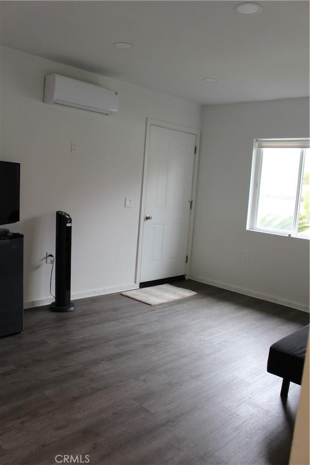unfurnished living room with recessed lighting, dark wood-style flooring, a wall mounted AC, and baseboards