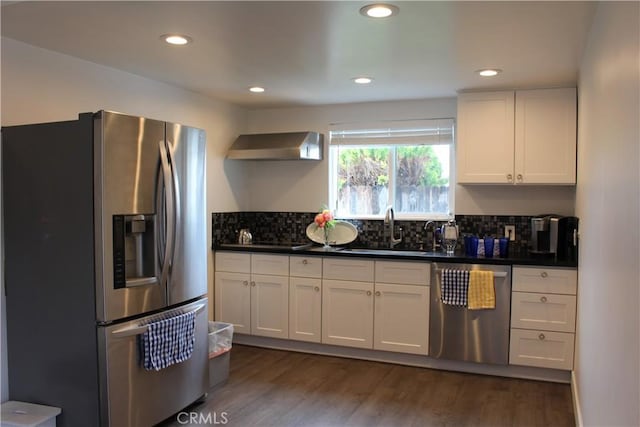 kitchen with a sink, dark countertops, stainless steel appliances, wall chimney exhaust hood, and backsplash